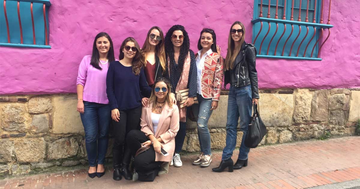 grupo de chicas posando para cámara y detrás una pared de color morado